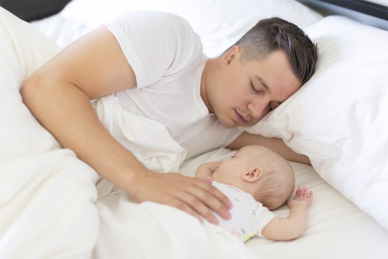 Padre durmiendo en colecho con su bebé